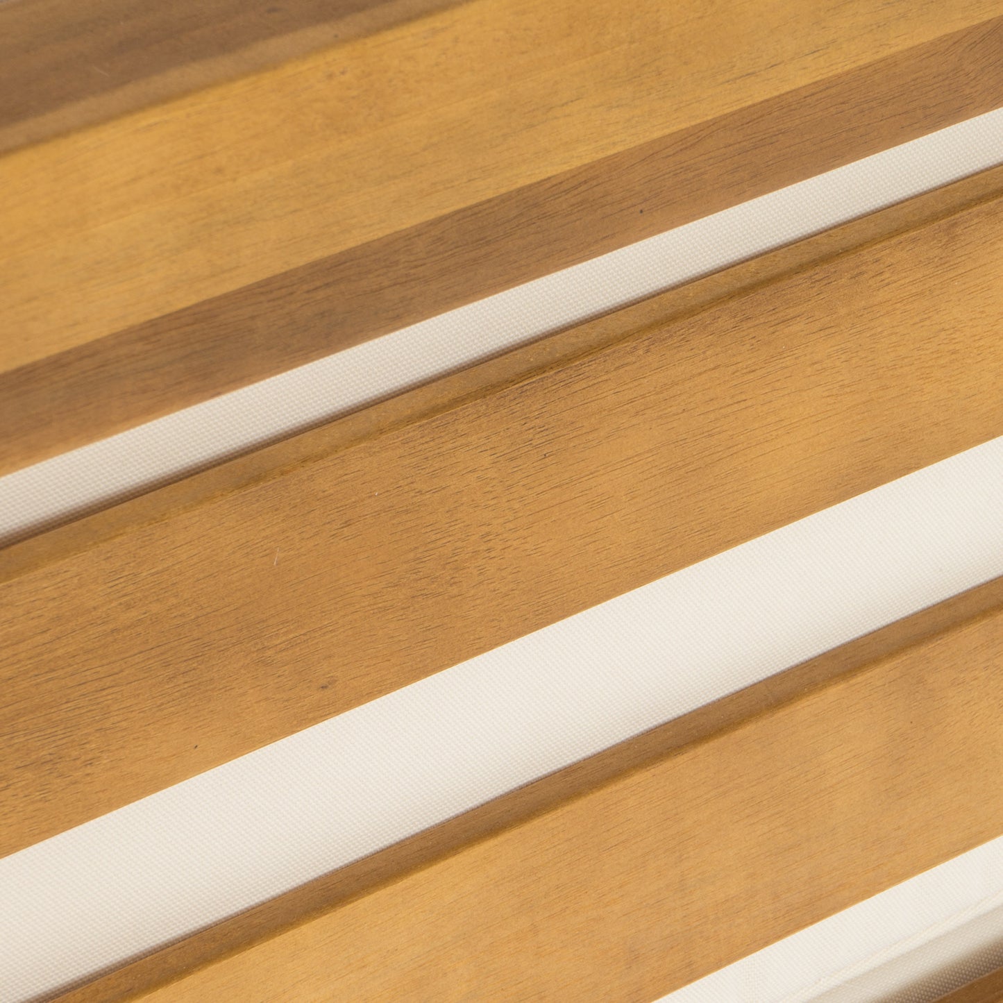 Closeup of warmtoned natural wood slats with cream fabric filling in between ideal for outdoor furniture