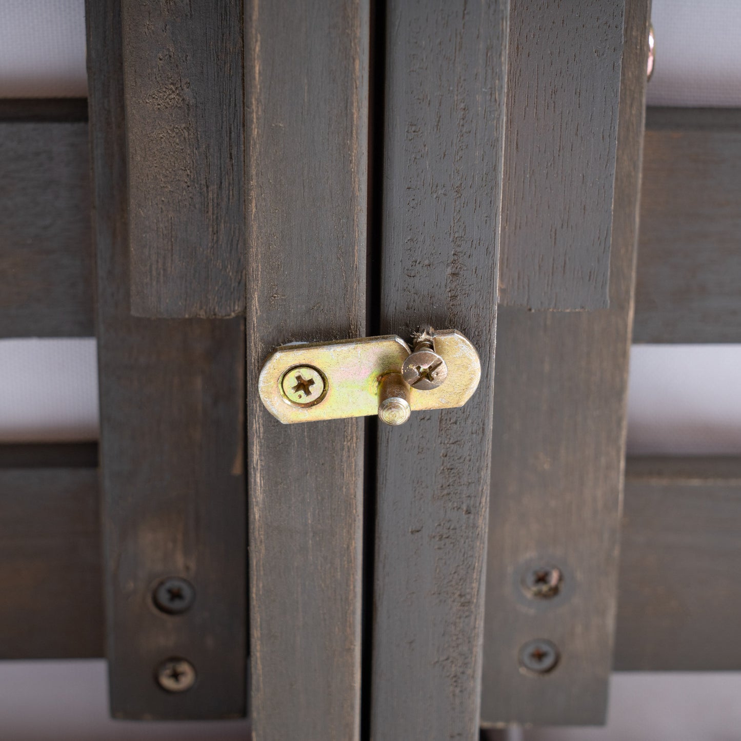 Dark gray wooden panel with metal latch and screws