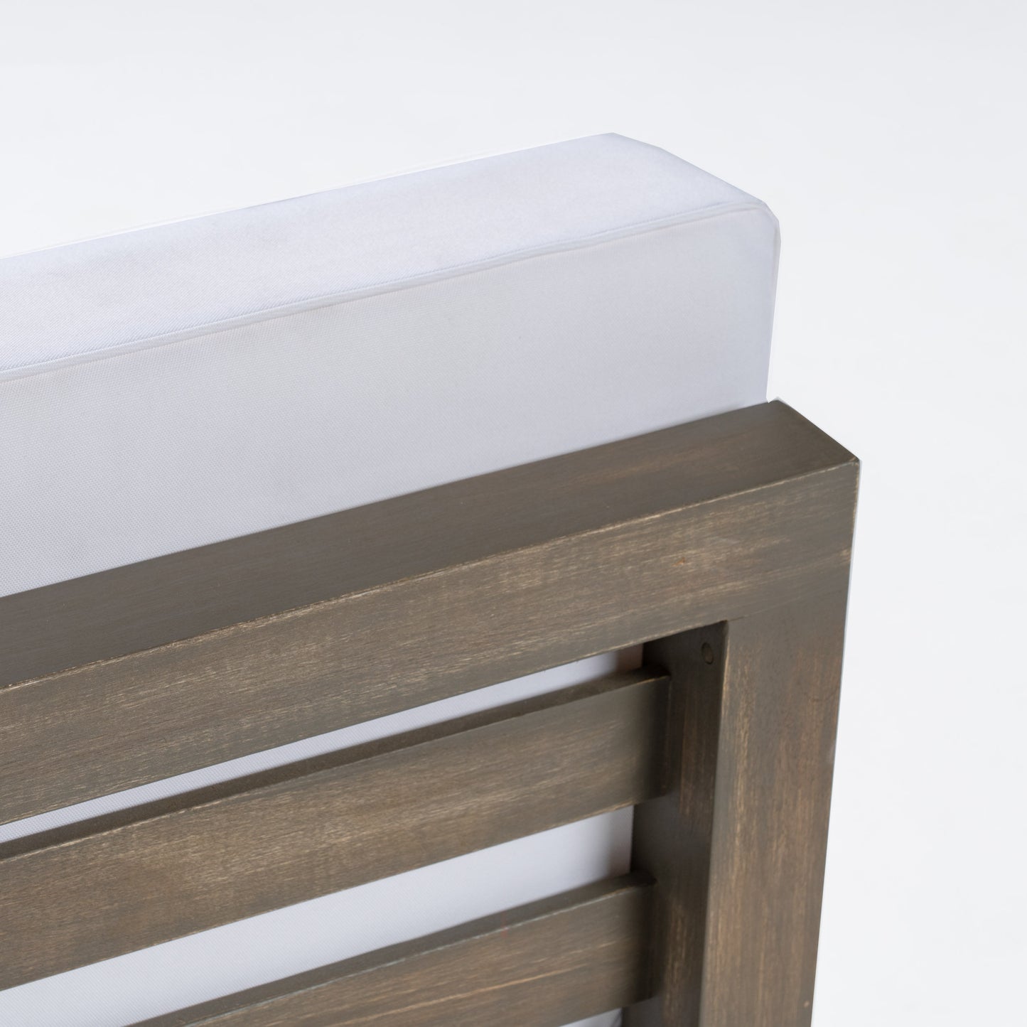 Closeup of a grey wood slatted chair frame with a white cushion detail perfect for outdoor seating