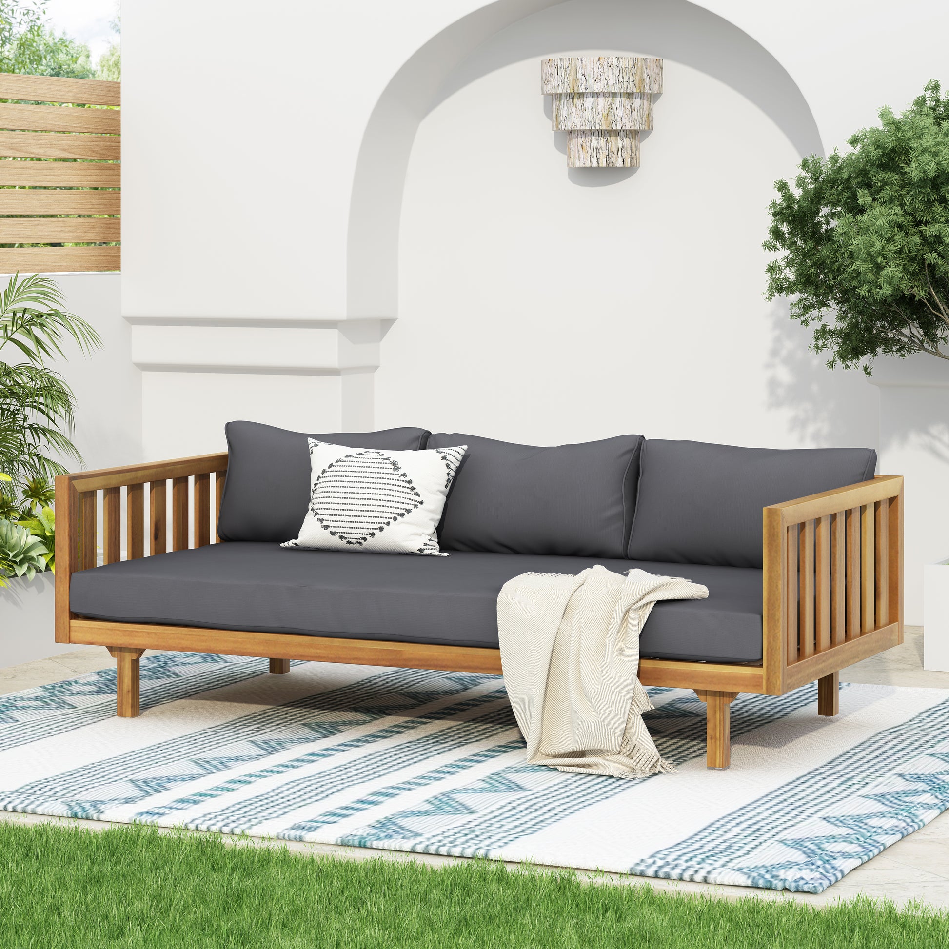 Wooden outdoor daybed with charcoal grey cushions and striped throw