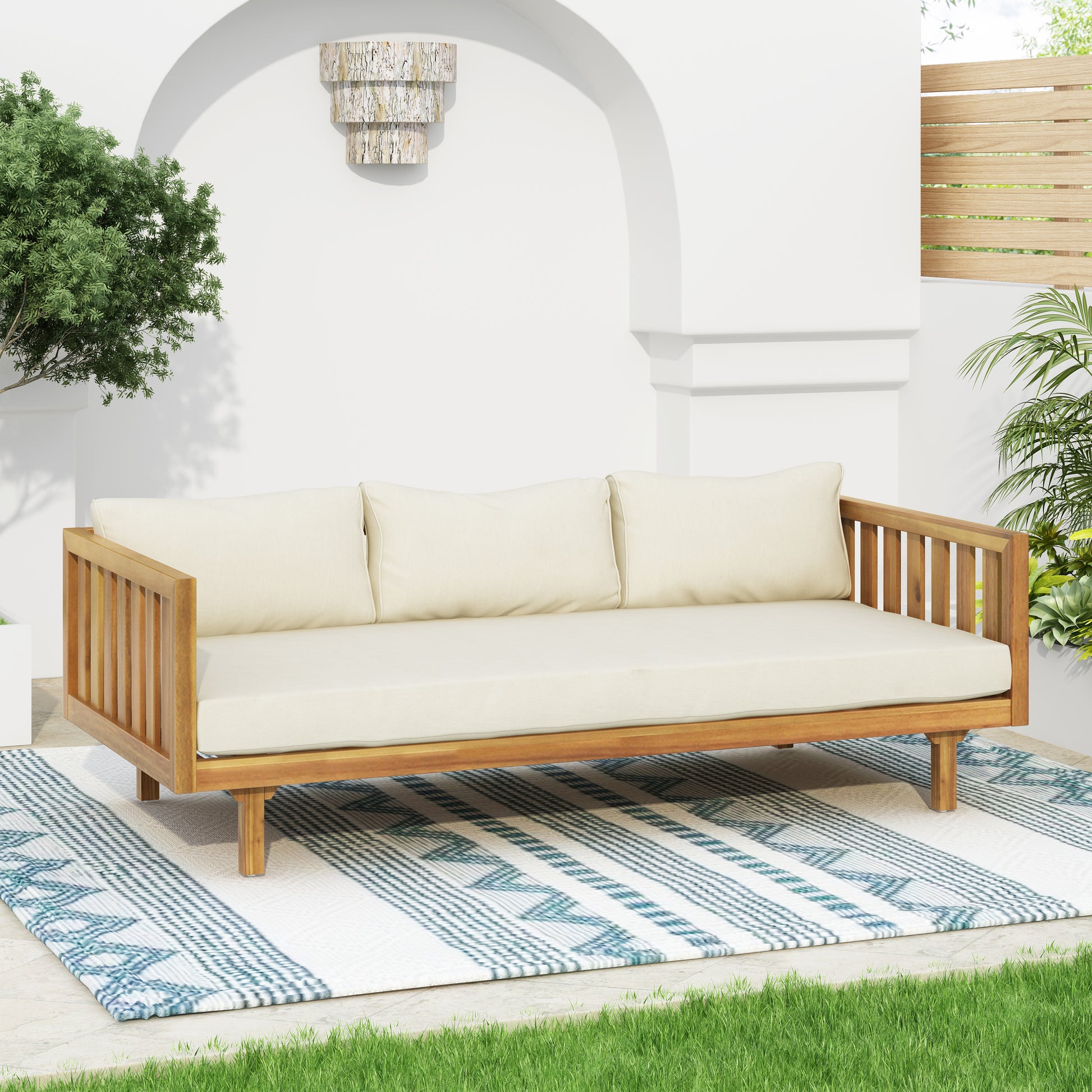 Wooden outdoor sofa with cream cushions on patterned rug