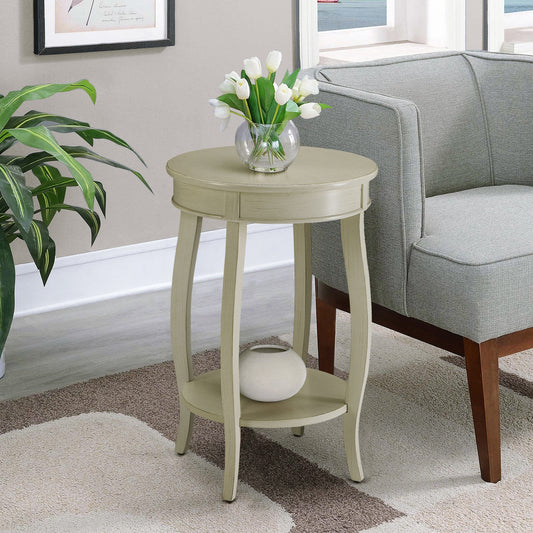 Creamcolored round end table with carved legs and a lower shelf