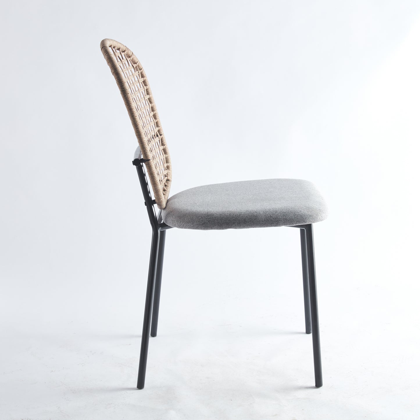Woven rattan back chair with a grey upholstered seat and black metal legs