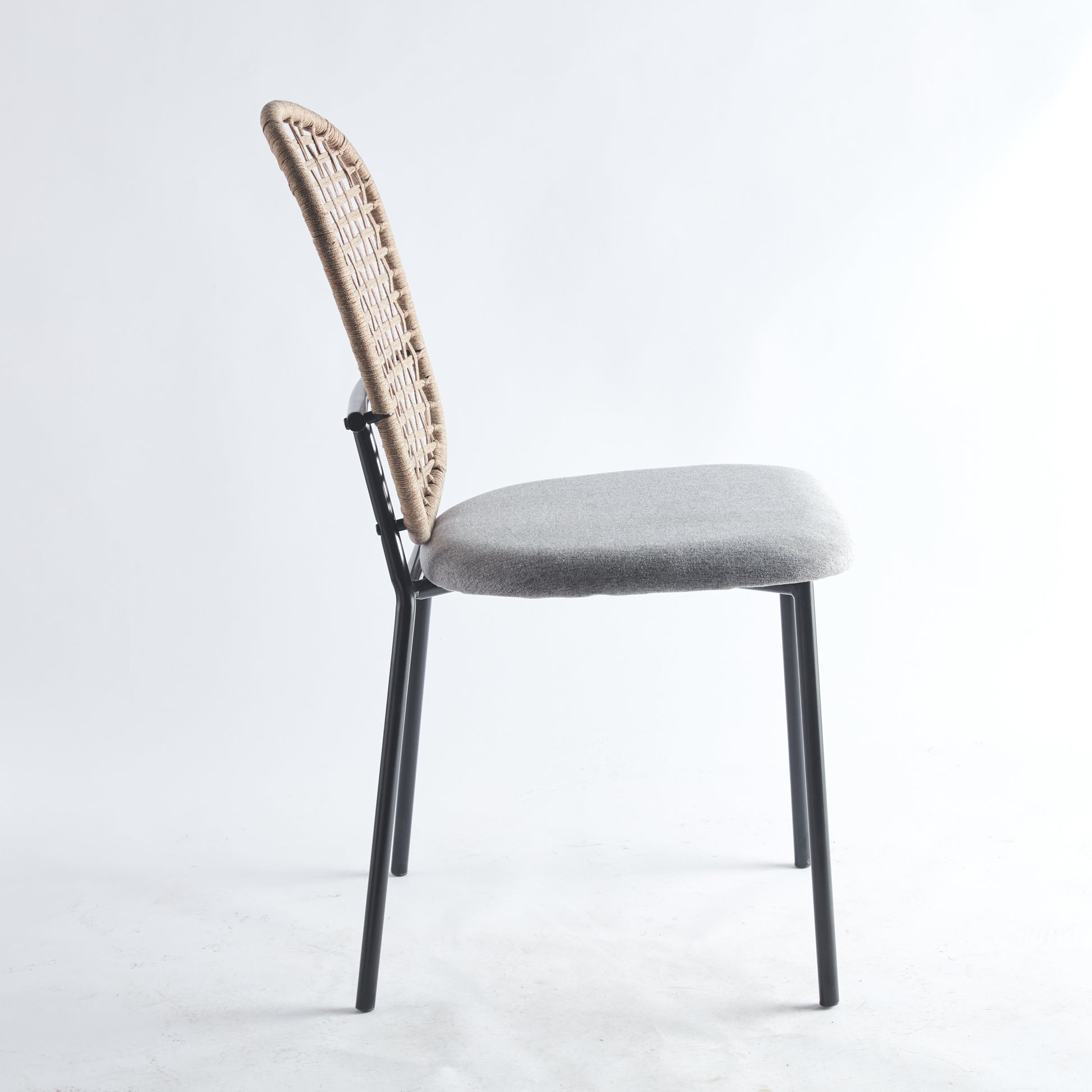 Woven rattan back chair with a grey upholstered seat and black metal legs