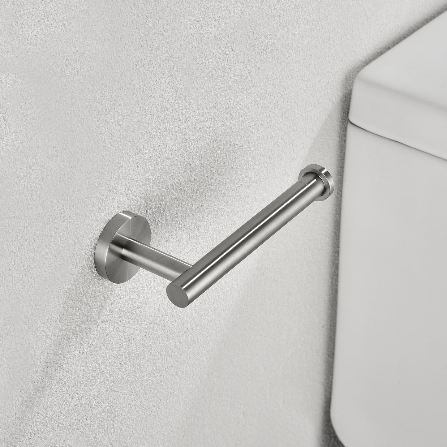 Brushed nickel toilet paper holder mounted on a textured white wall