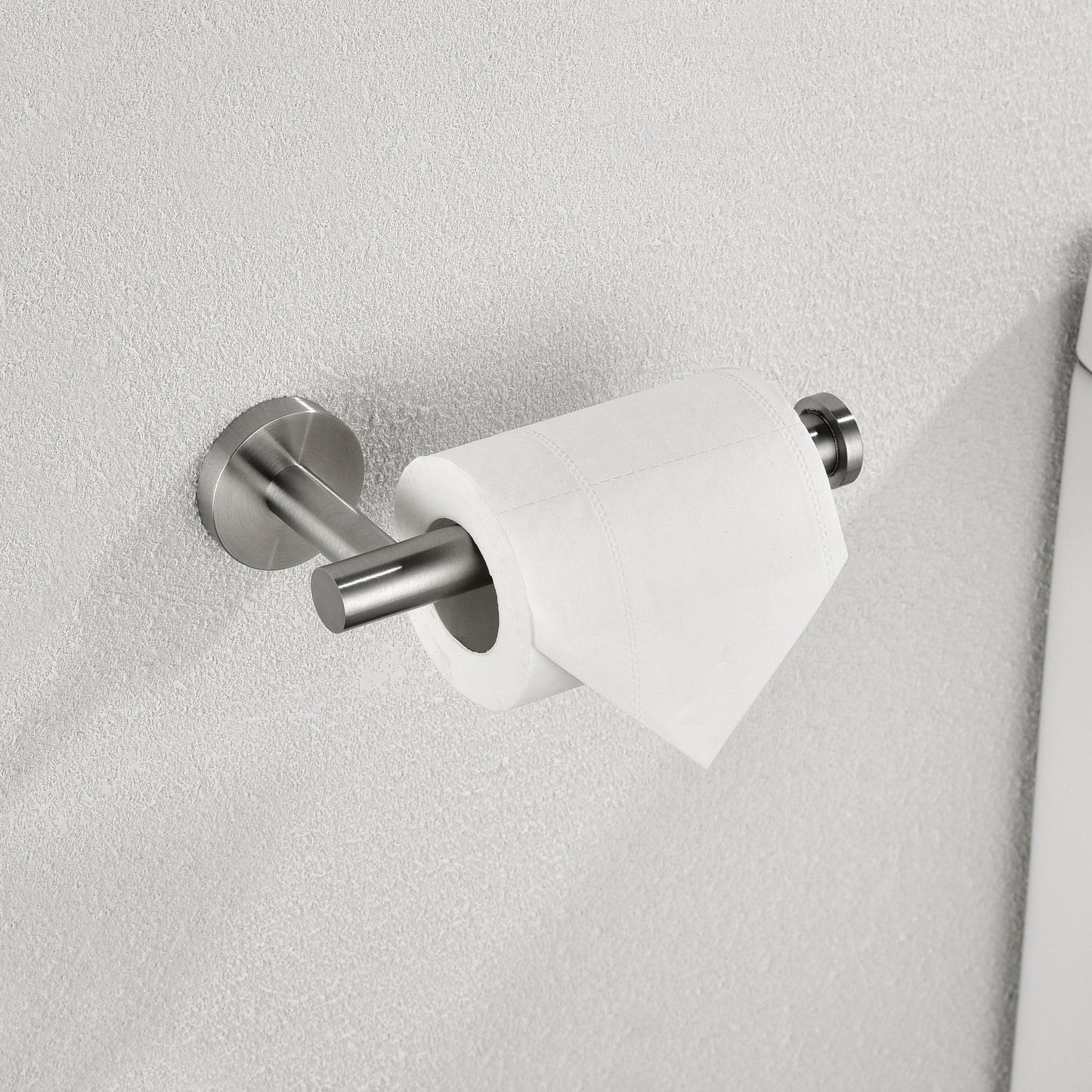 Brushed nickel toilet paper holder mounted on a textured gray wall with a white toilet paper roll