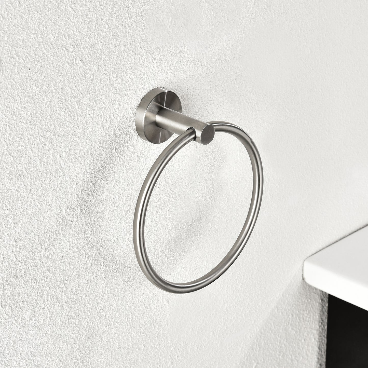 Brushed nickel round towel ring mounted on textured white wall