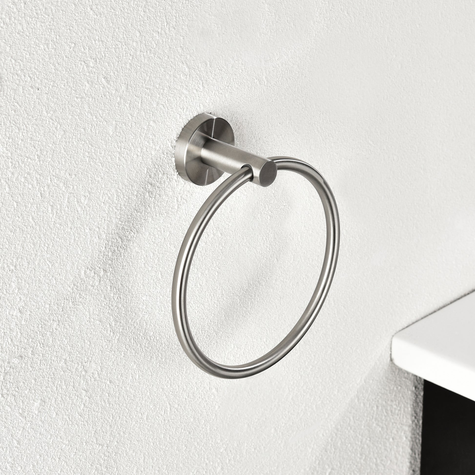 Brushed nickel round towel ring mounted on textured white wall
