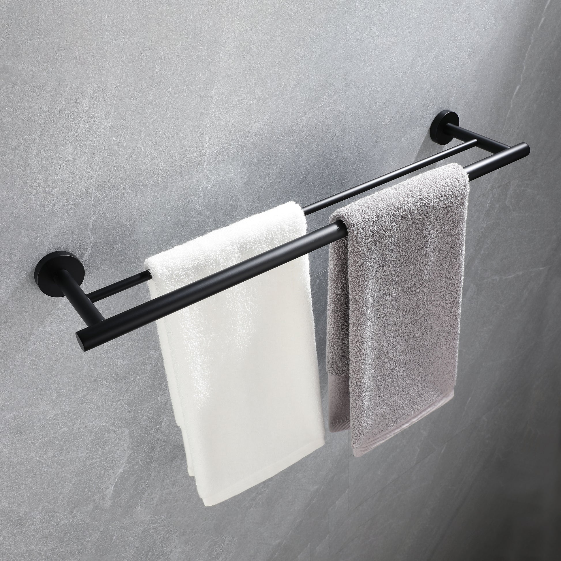 Black double towel rack holding white and grey towels on textured grey wall