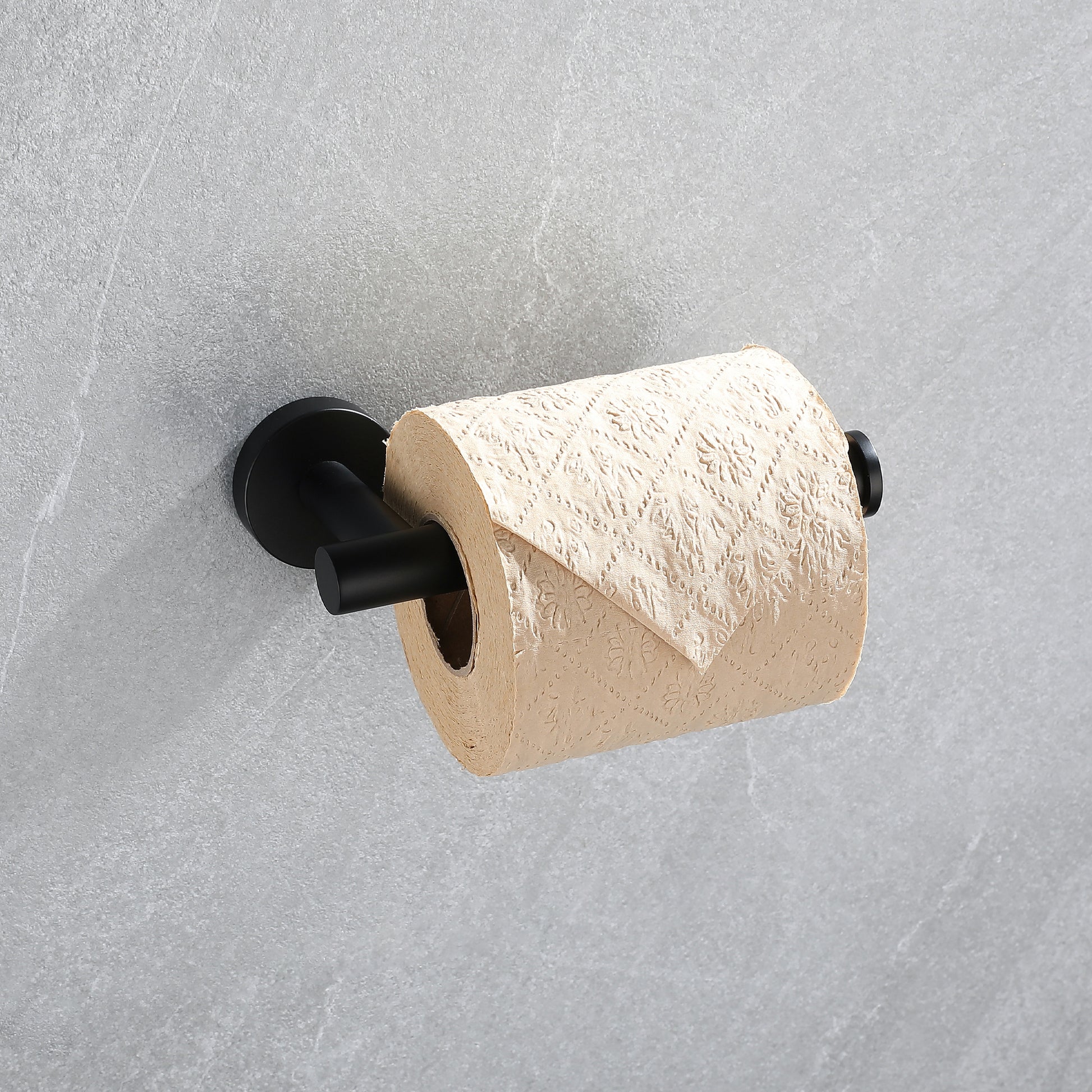 Black toilet paper holder with a full roll of tan patterned toilet paper