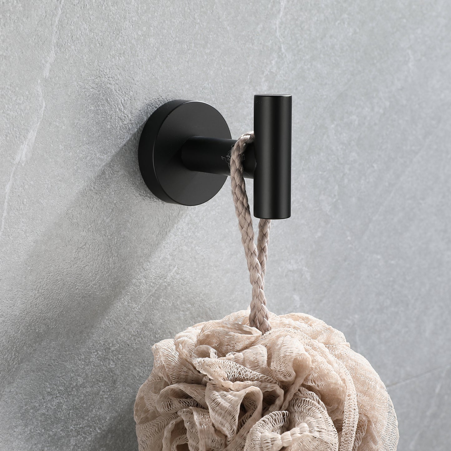 Black modern bathroom hook holding a bath pouf with a rope