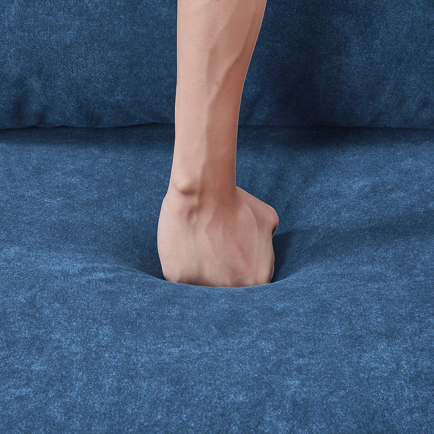 Blue textured fabric sofa with a hand demonstrating plush comfort