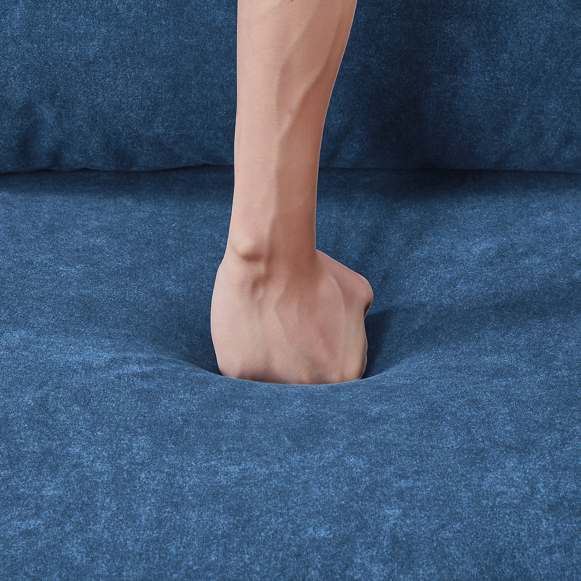 Blue textured fabric sofa with a hand demonstrating plush comfort