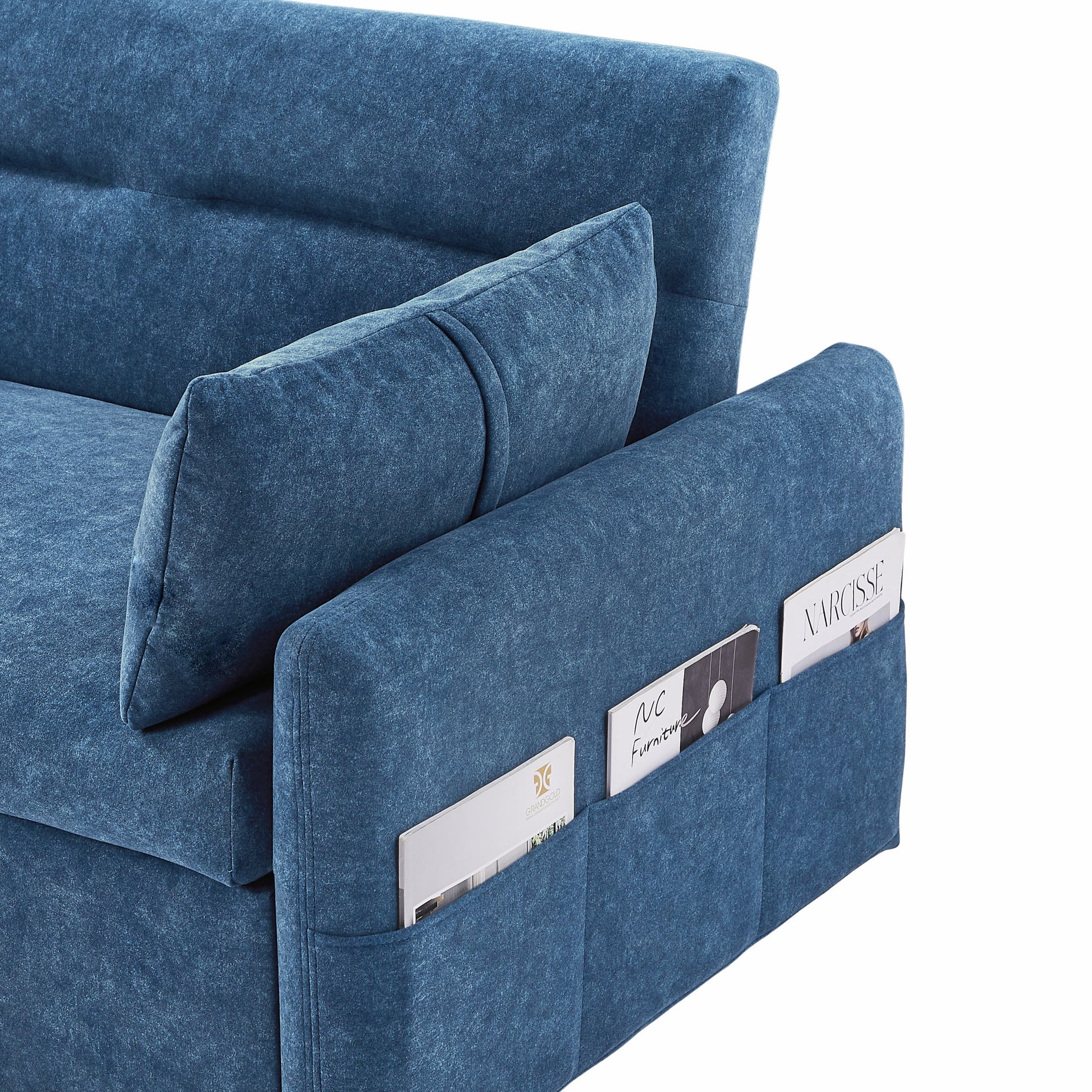 Closeup of a blue velvet sofa armrest with builtin magazine pockets holding publications
