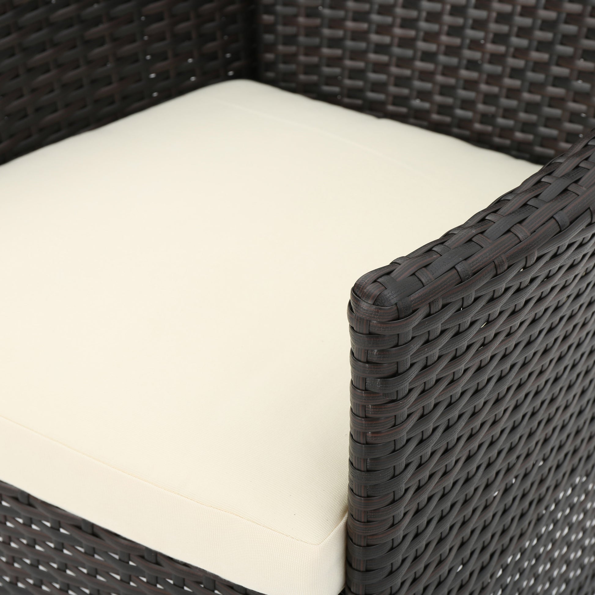 Dark brown wicker armchair with a cream seat cushion perfect for patio decor