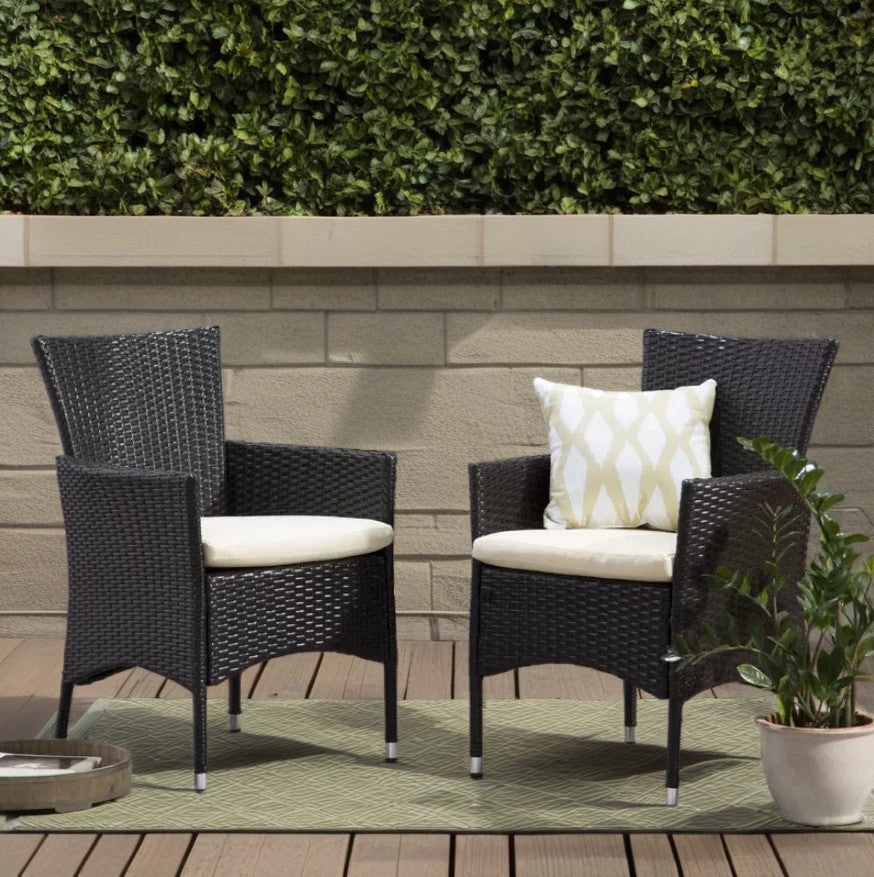 Two dark brown rattan patio chairs with cream cushions one with a diamondpatterned pillow