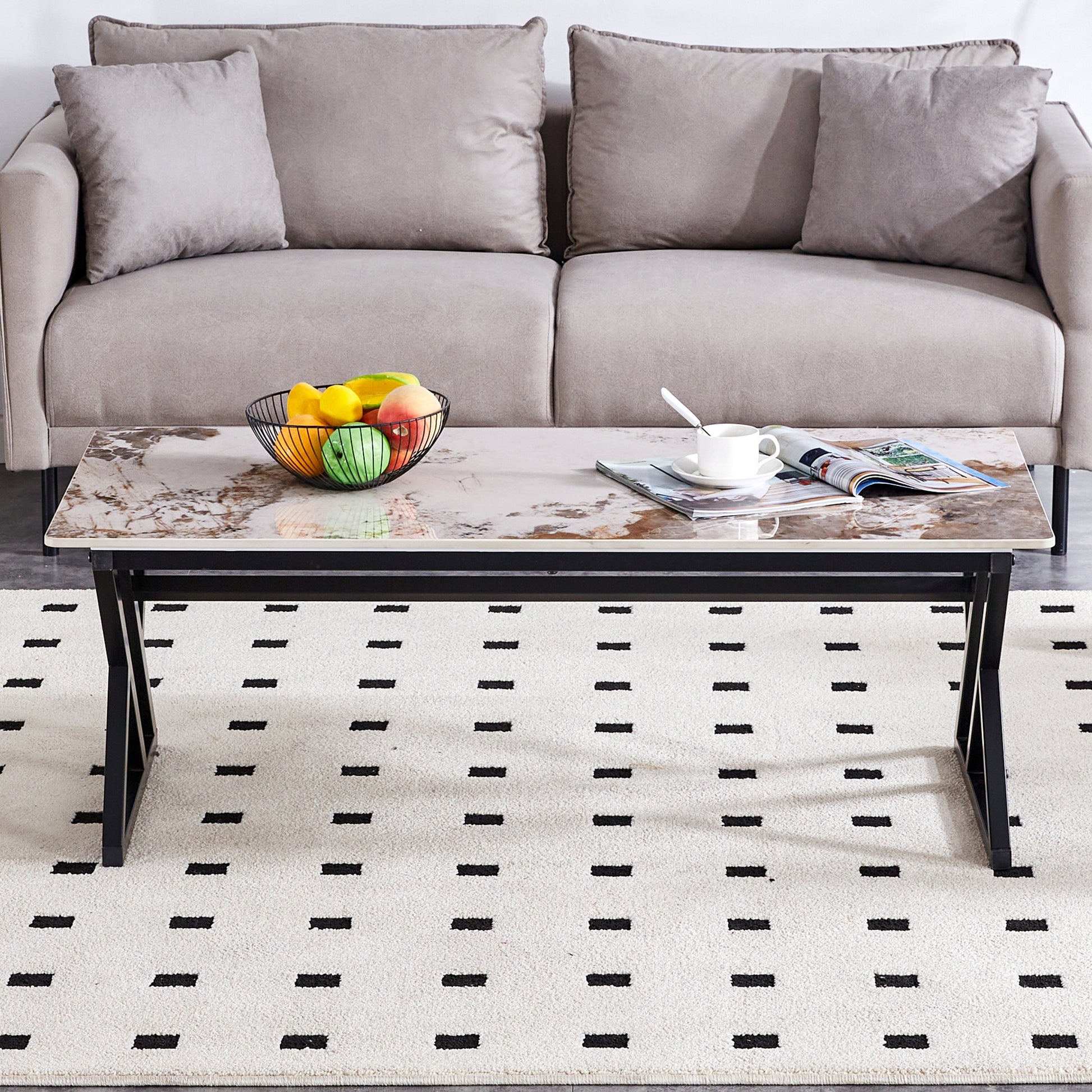 Rectangular marble effect coffee table with black metal legs and a fruit bowl