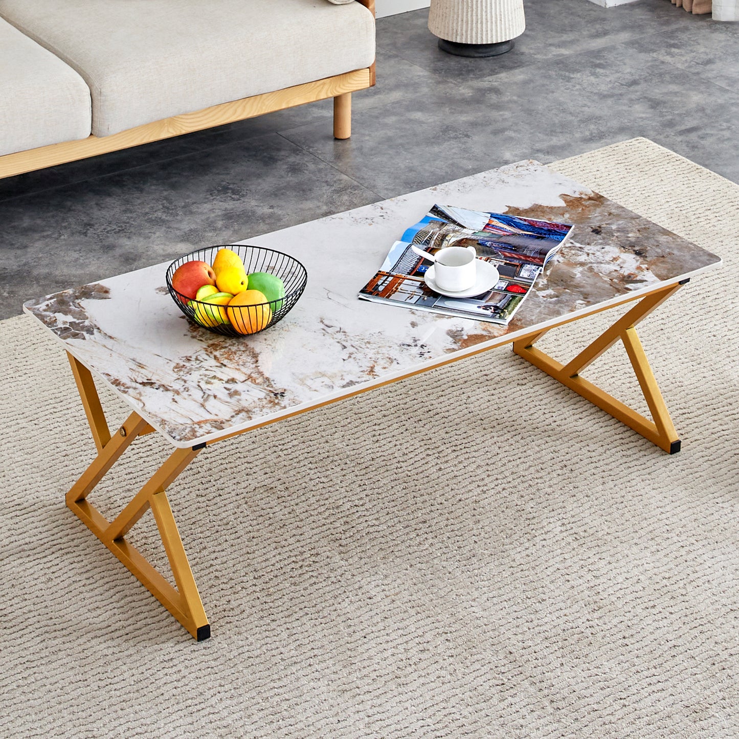 Modern faux marble coffee table with gold geometric legs and a fruit bowl