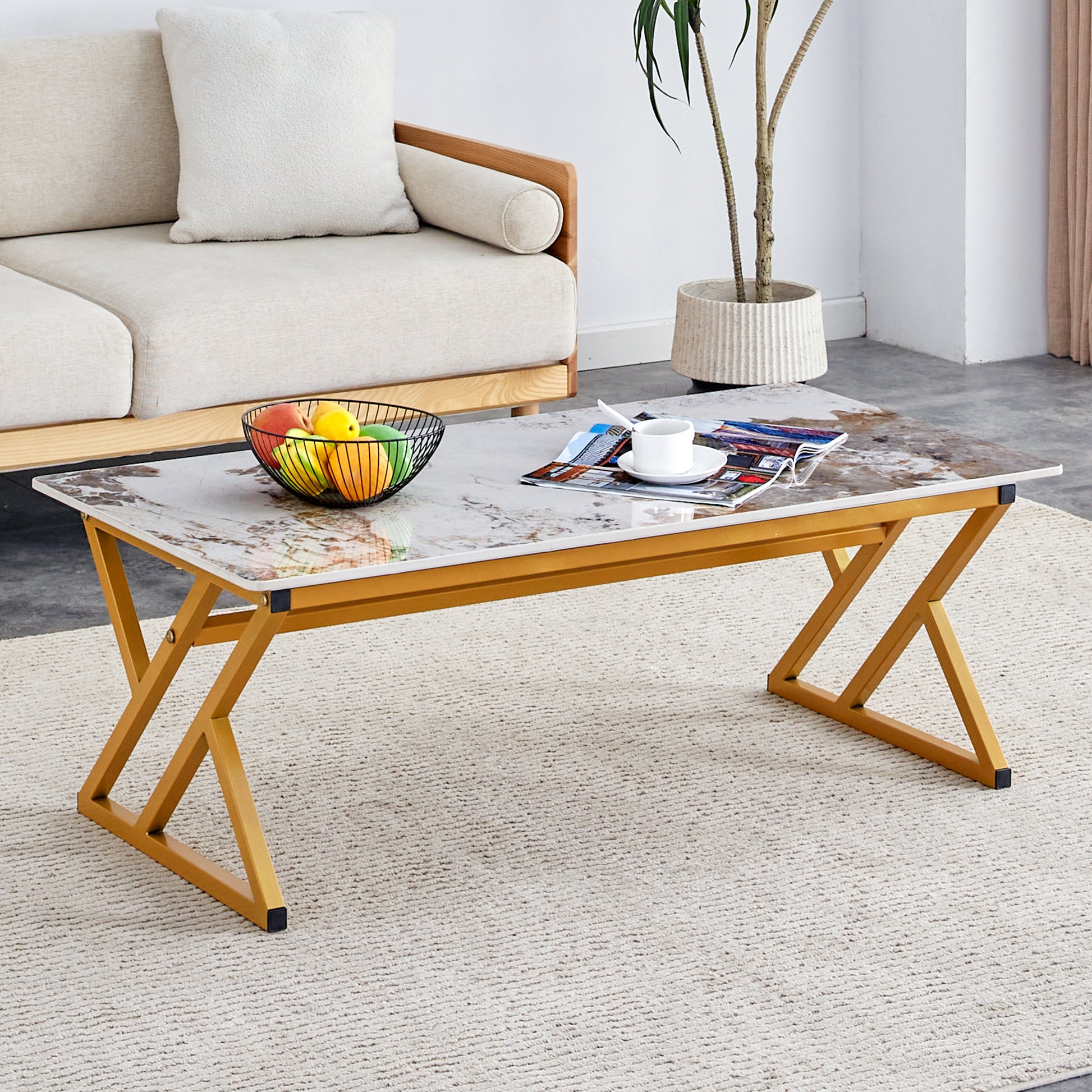 Gold metal frame coffee table with marblepatterned top and a fruit bowl