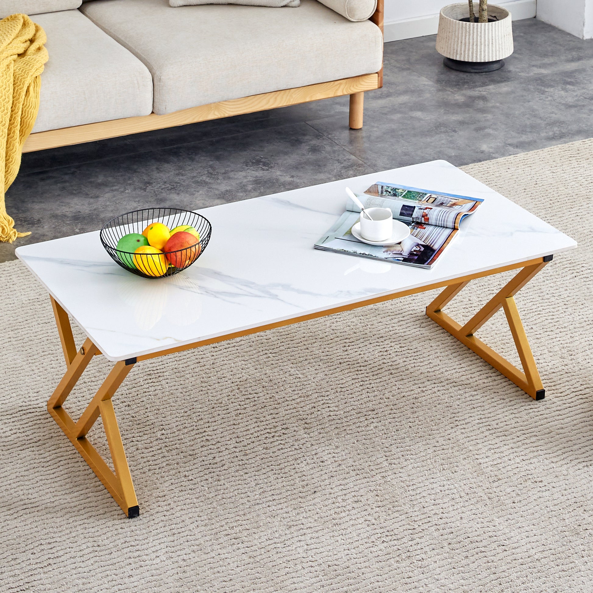 Marblelook folding coffee table with gold geometric legs on a textured rug