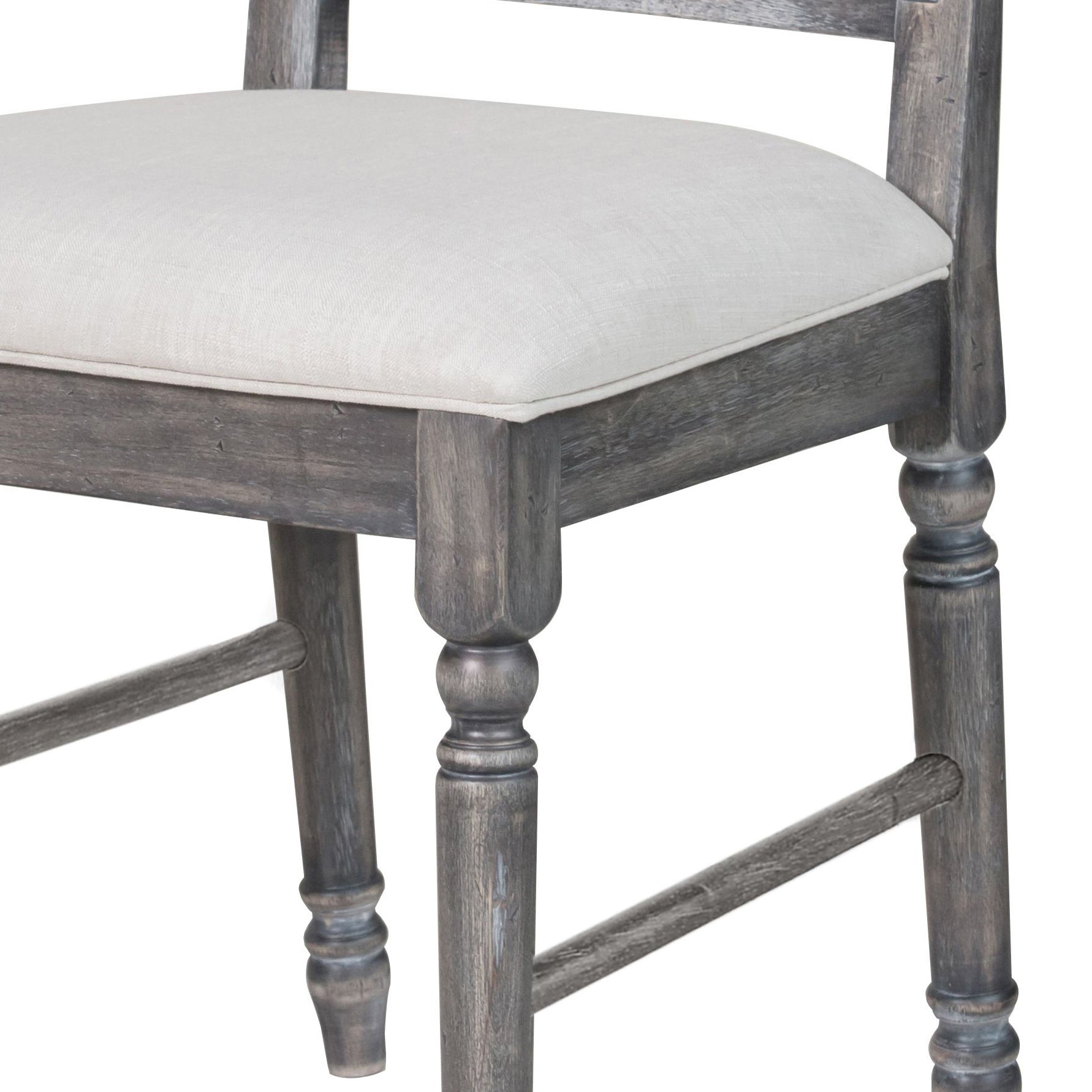 Closeup of a distressed gray wooden bar stool leg with a beige linen upholstered seat cushion