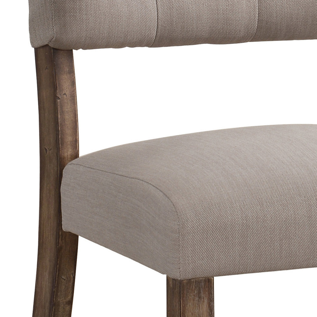 Tufted back and upholstered seat of a grey fabric dining chair with distressed wood legs