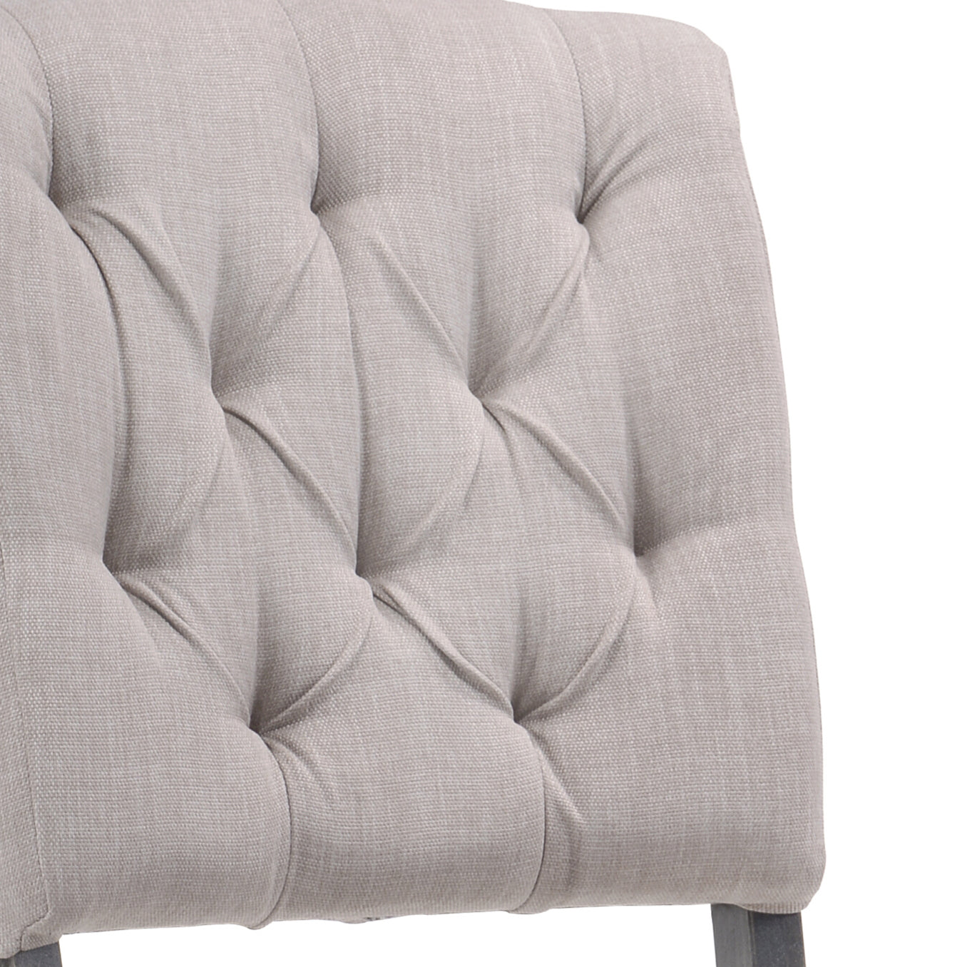 Closeup of tufted beige upholstered chair back with button detailing