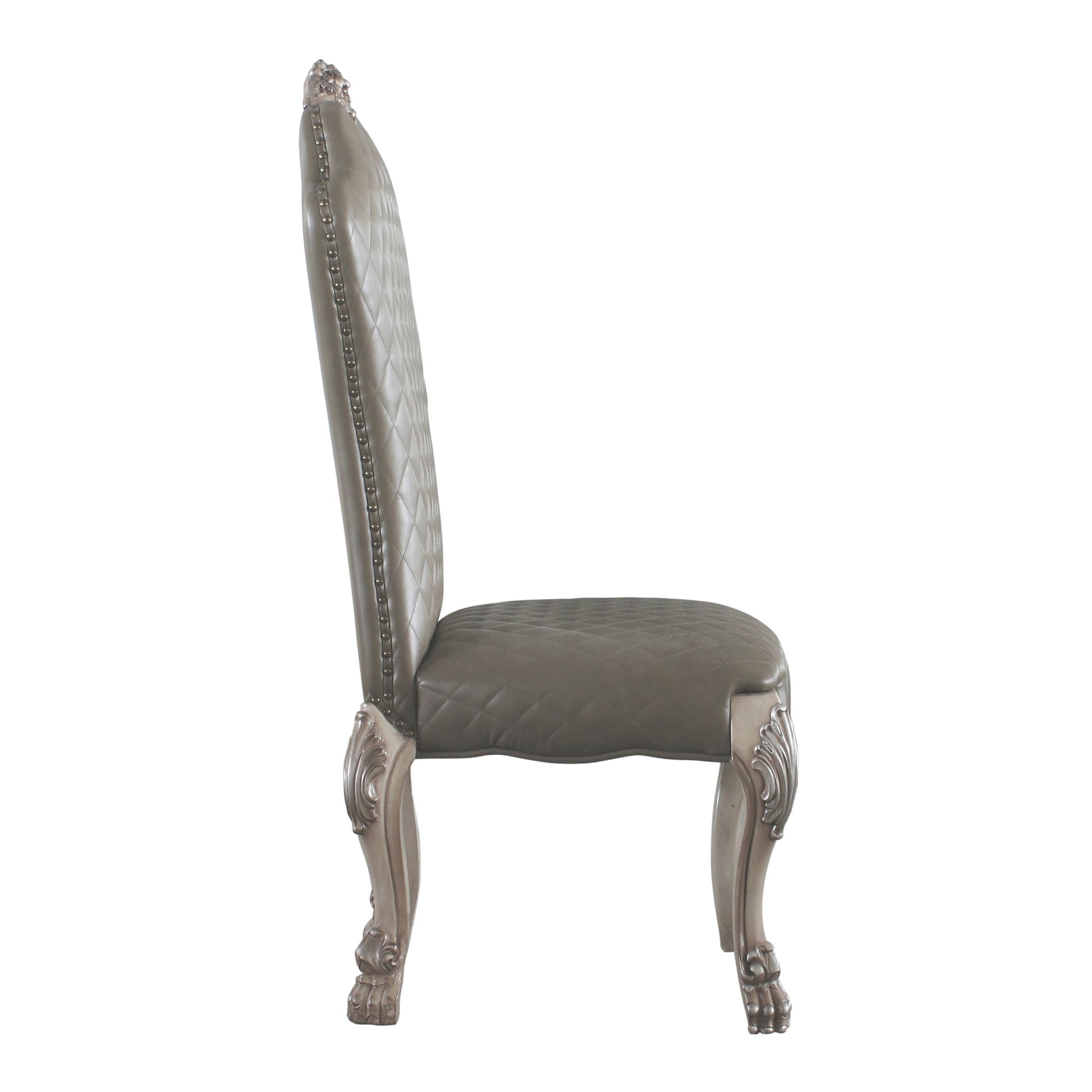 Side profile of a tufted grey leather dining chair with silver nailhead trim and ornate carved legs