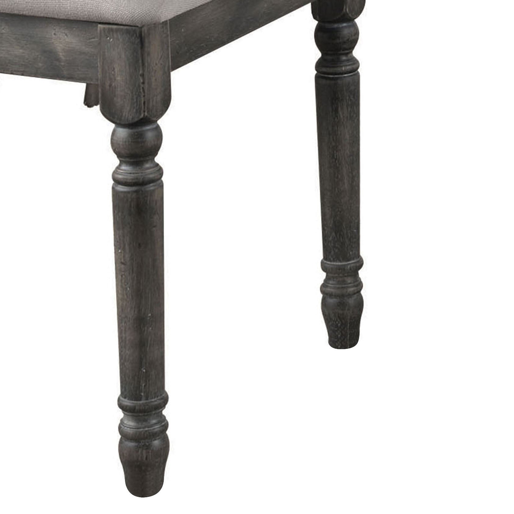 Rustic dark wood turned leg of a dining chair with upholstered seat