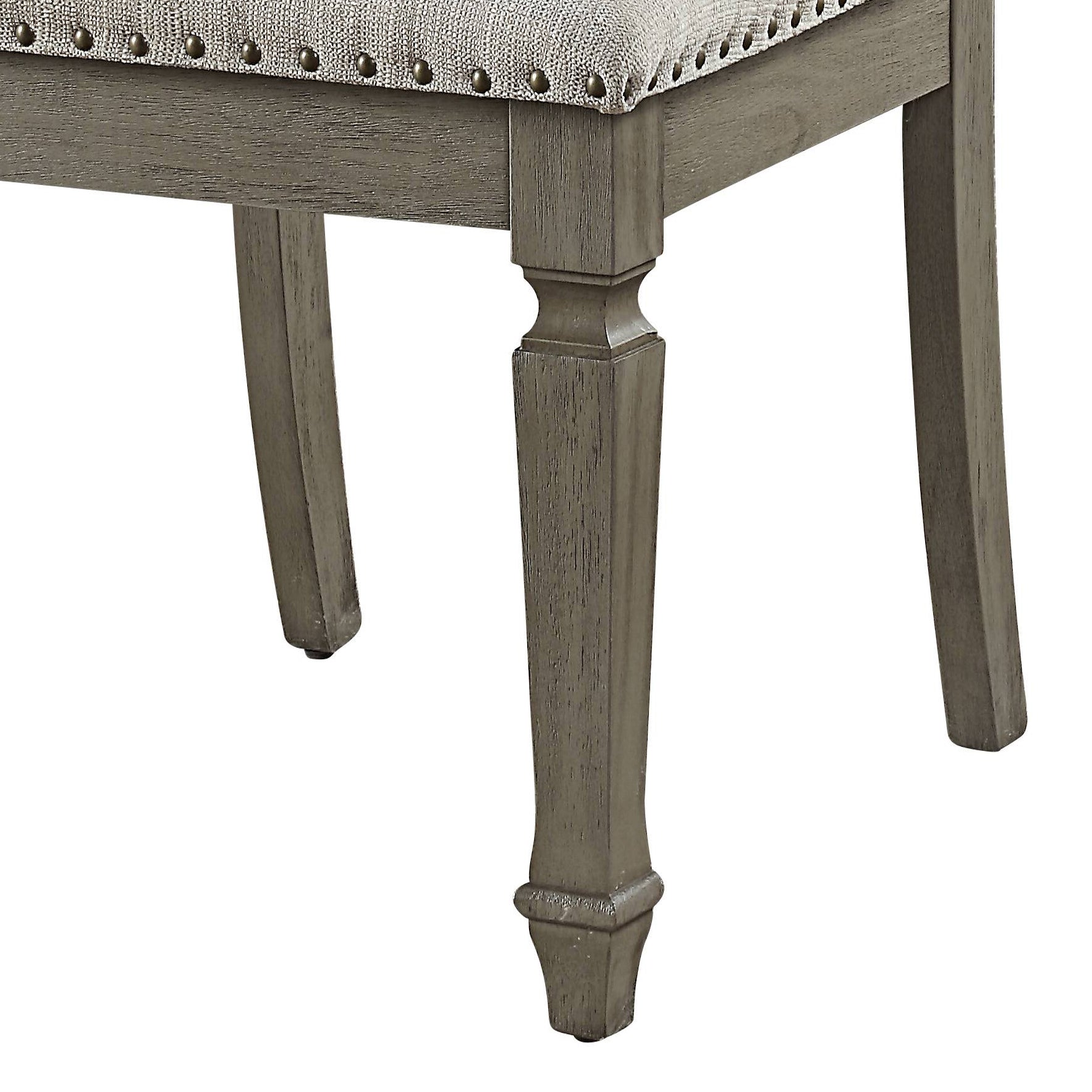 Closeup of upholstered chair leg with nailhead trim detail and distressed wood finish