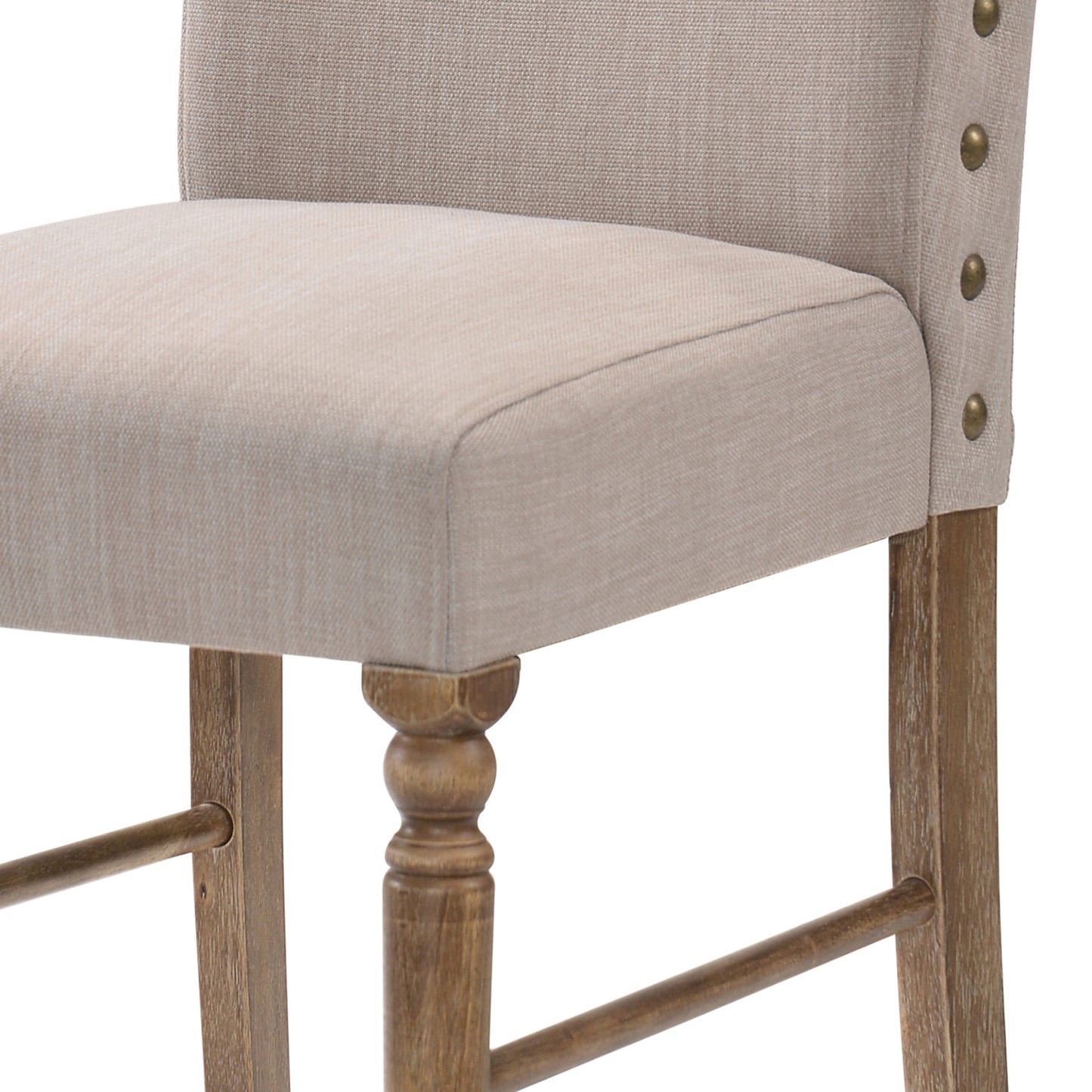 Closeup of a beige upholstered bar stool with brass nailhead trim and wooden legs