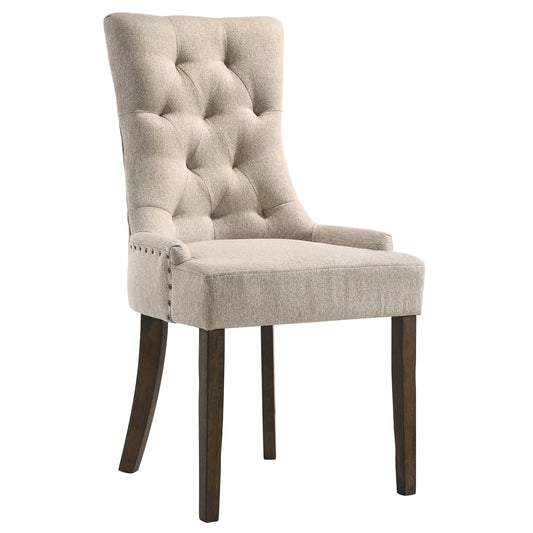 Tufted beige linen dining chair with dark wood legs and bronze nailhead trim