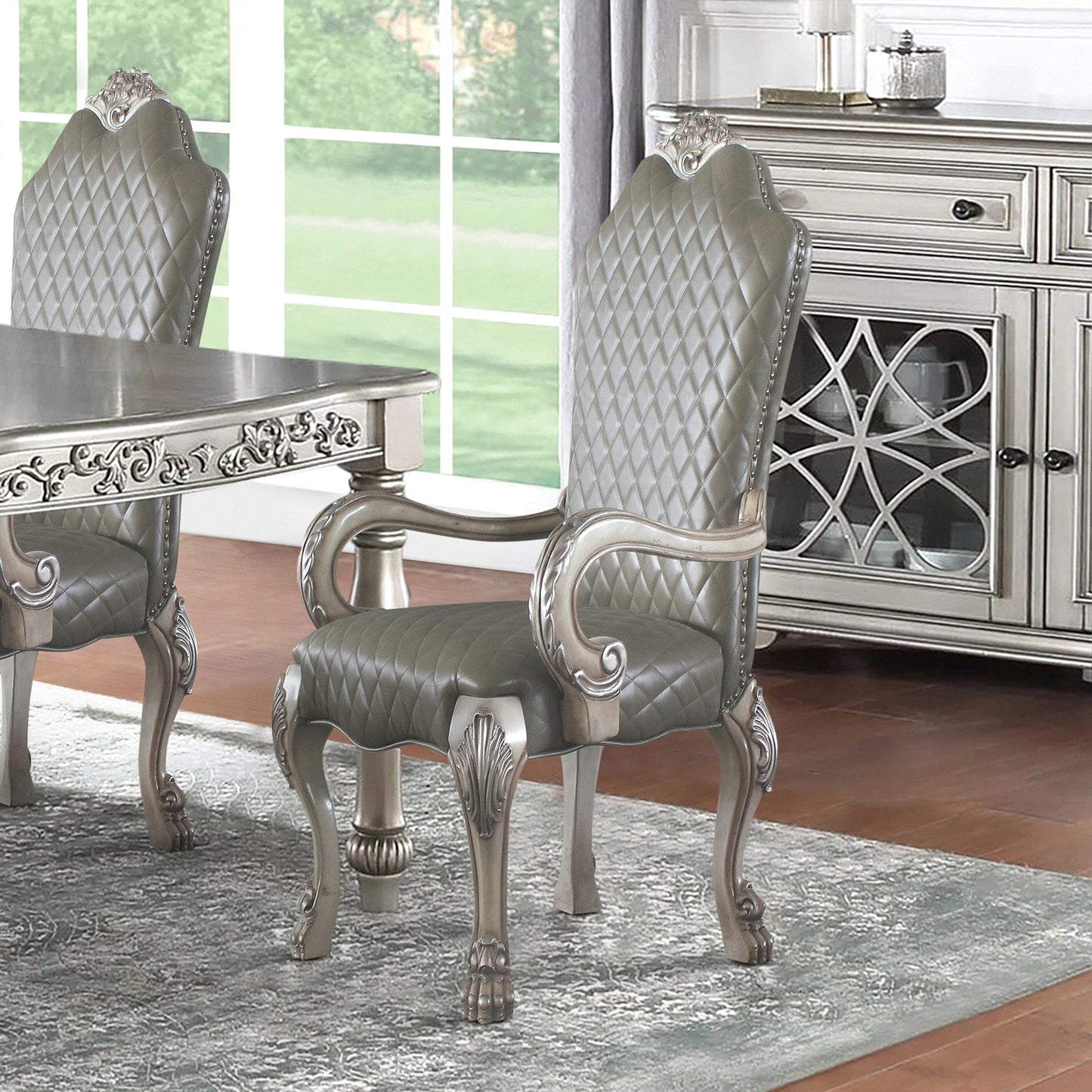 Gray tufted arm dining chair with carved details and ornate legs