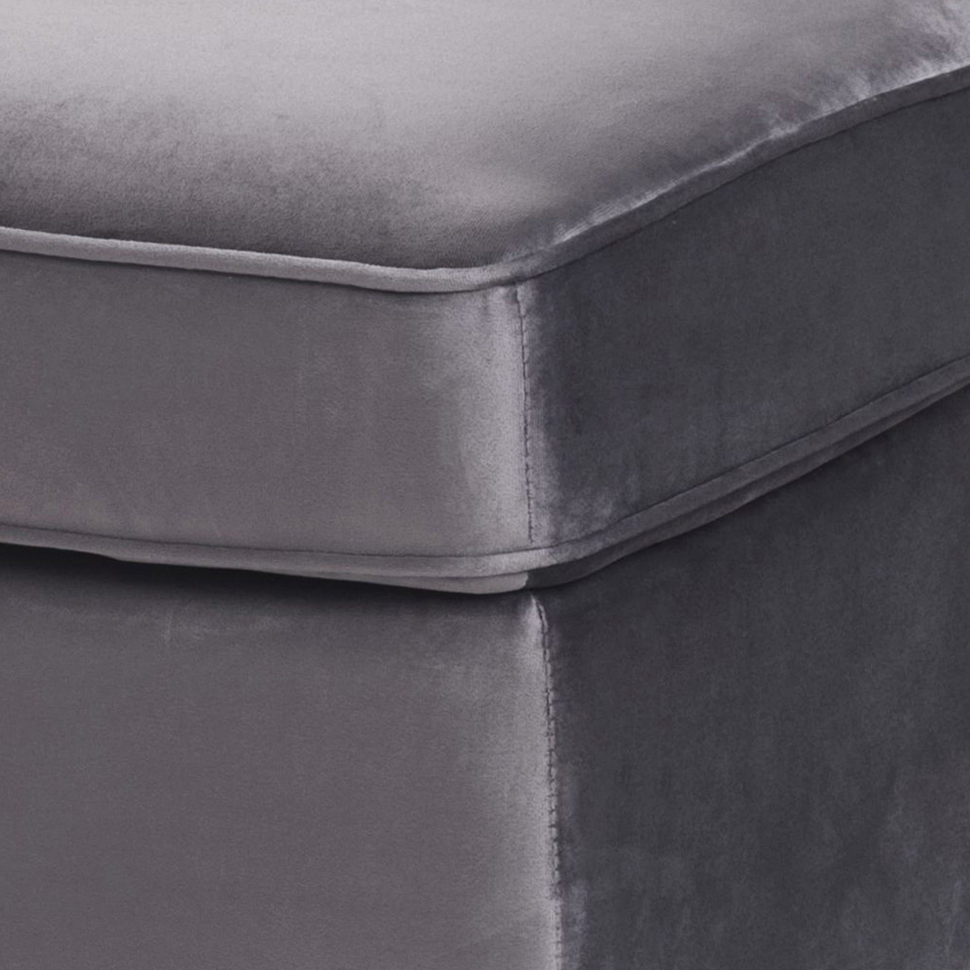 Closeup of a charcoal grey velvet ottoman with clean stitching detail