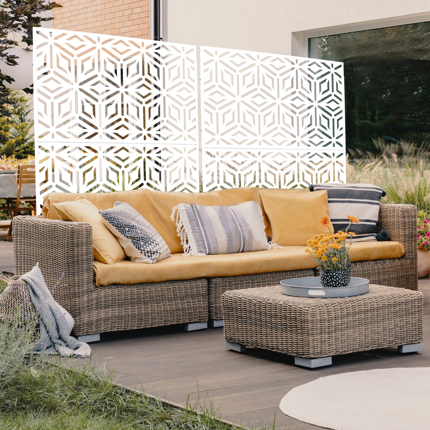 White decorative outdoor privacy screen with geometric pattern on patio beside wicker furniture