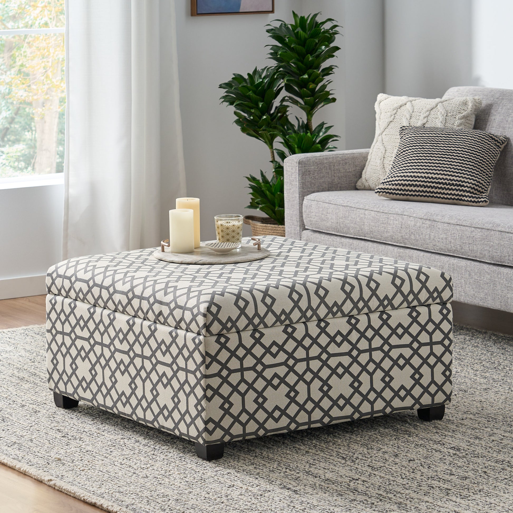 Storage ottoman with gray geometric pattern upholstery and dark wooden legs