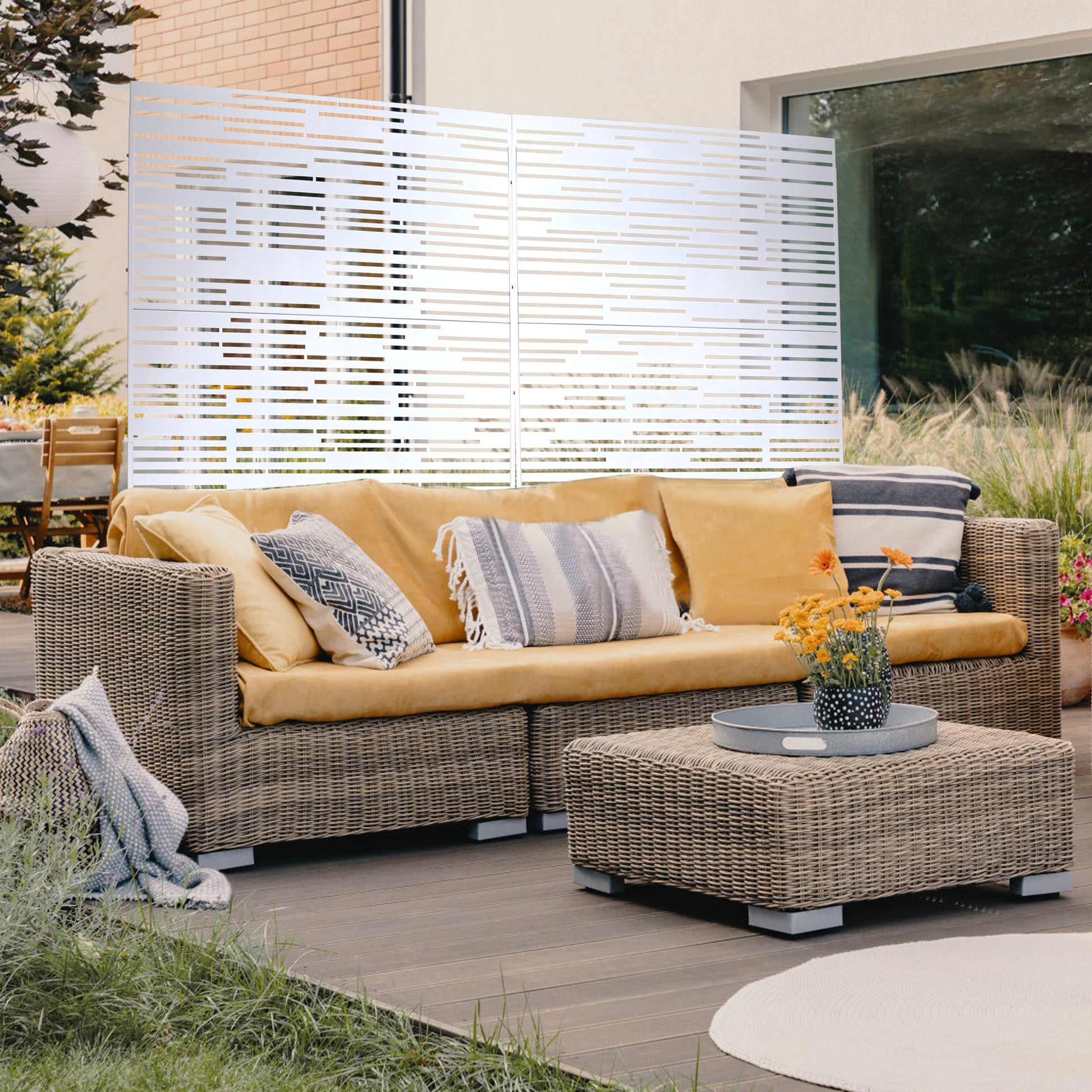 Wicker outdoor sofa with mustard yellow cushions and decorative pillows on a wooden deck