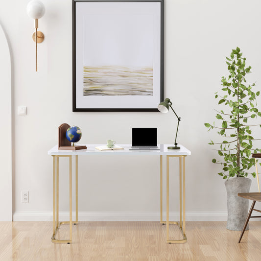 Modern white desk with gold metal legs featuring a laptop book and mug