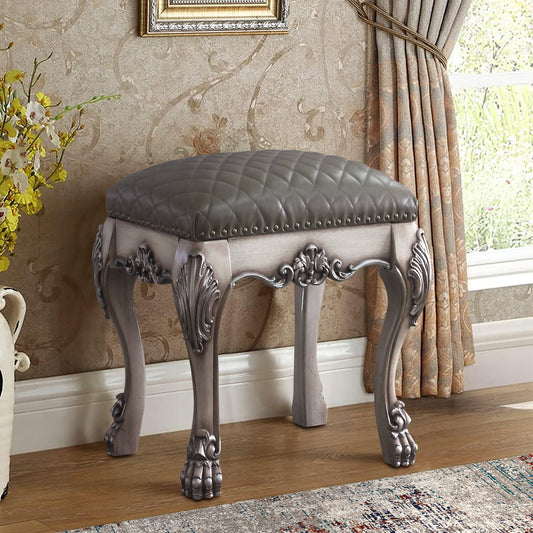 Gray tufted upholstered vanity stool with ornate carved legs and silver nailhead trim