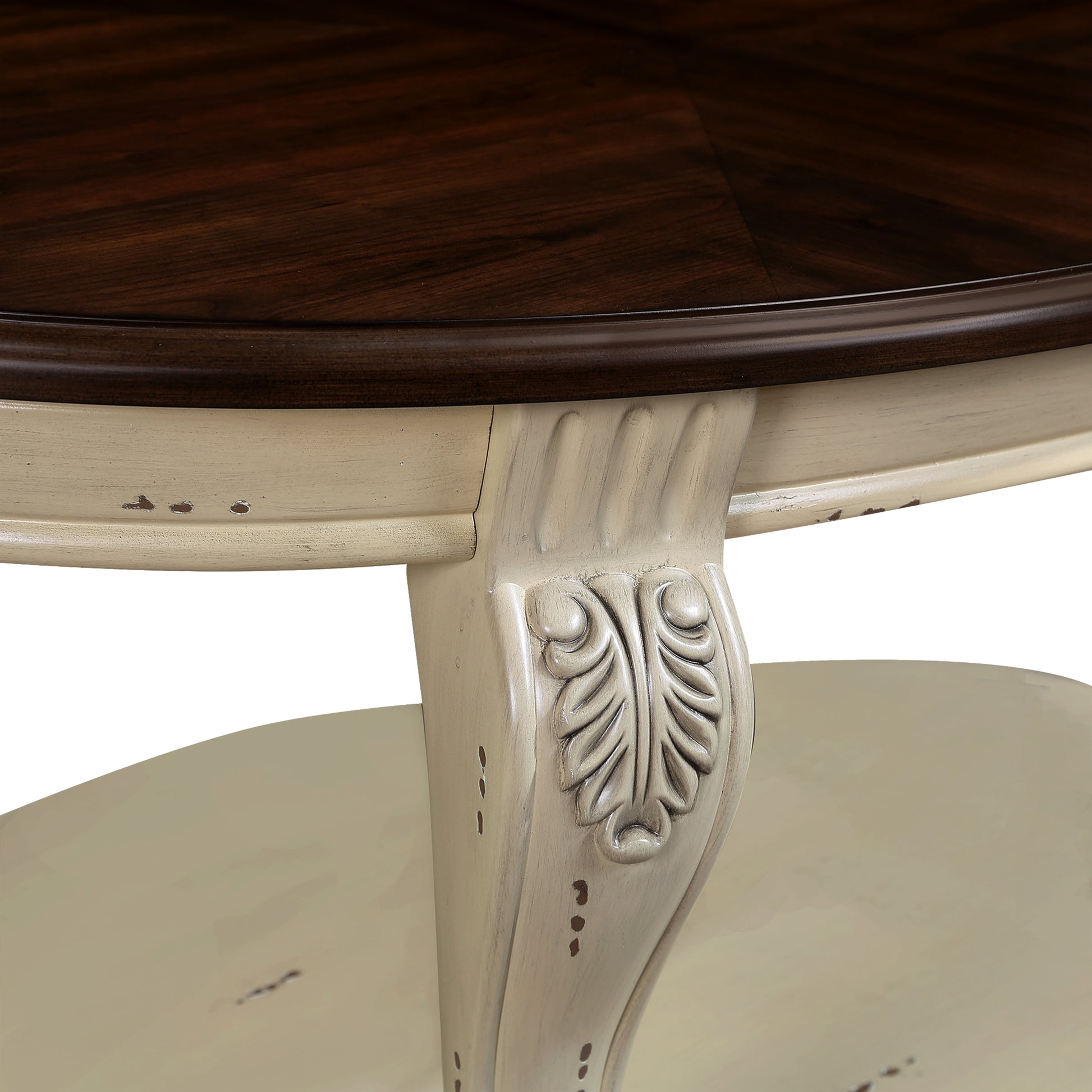 Ornate carved leg of a distressed cream wood table with dark wood tabletop