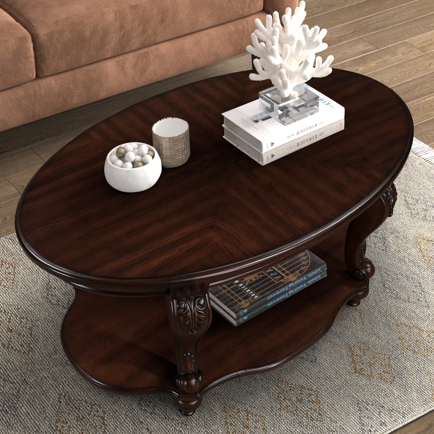 Dark wood oval coffee table with ornate legs and a lower shelf displaying books