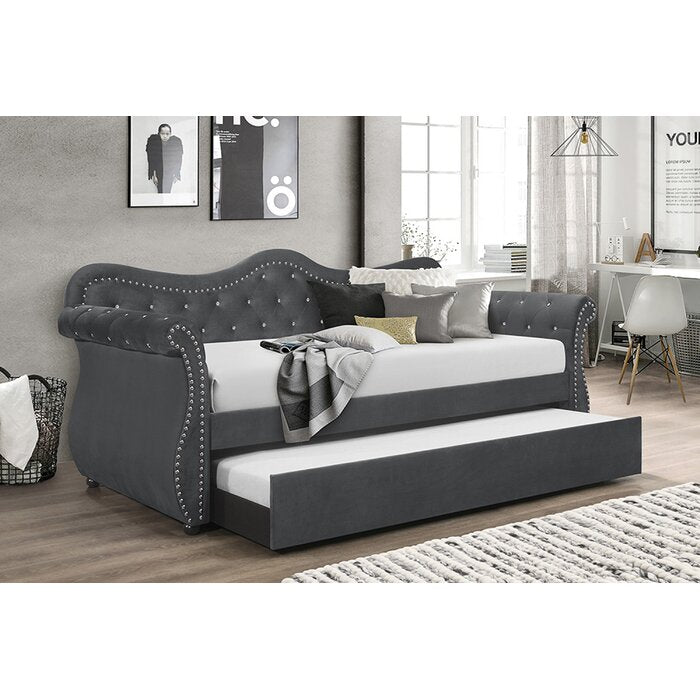 Dark gray upholstered daybed with pullout trundle tufted back and nailhead trim