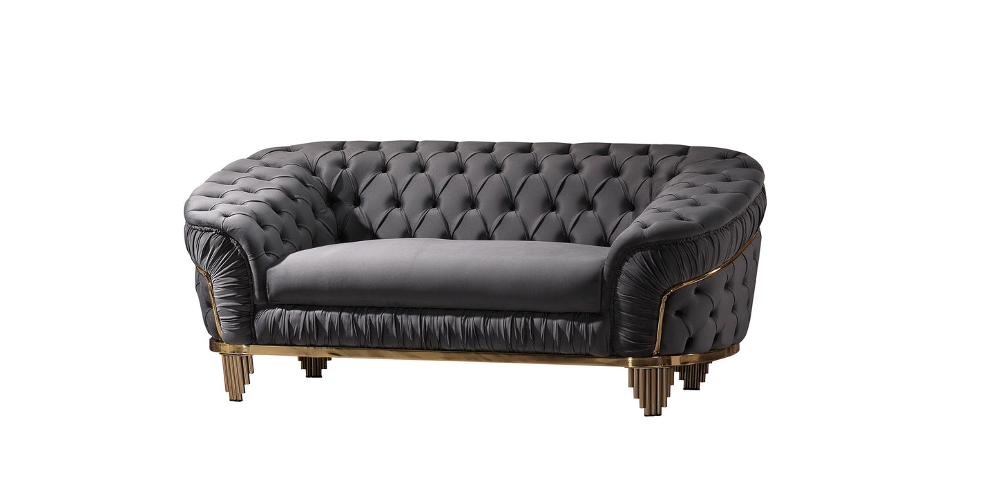 Dark grey tufted armchair with gold trim and fluted legs