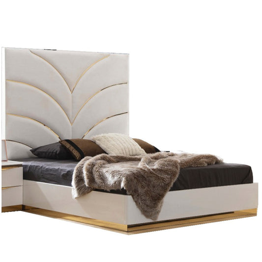 White upholstered queen bed with gold trim and decorative headboard