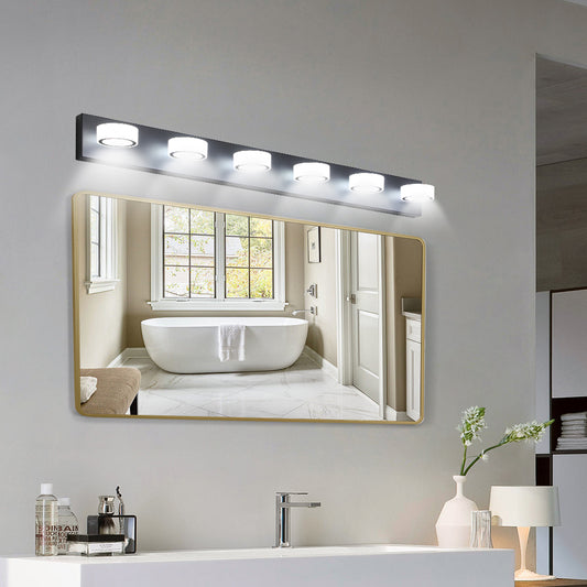 Modern gold framed bathroom mirror with a sleek vanity light fixture above reflecting a clean bathtub