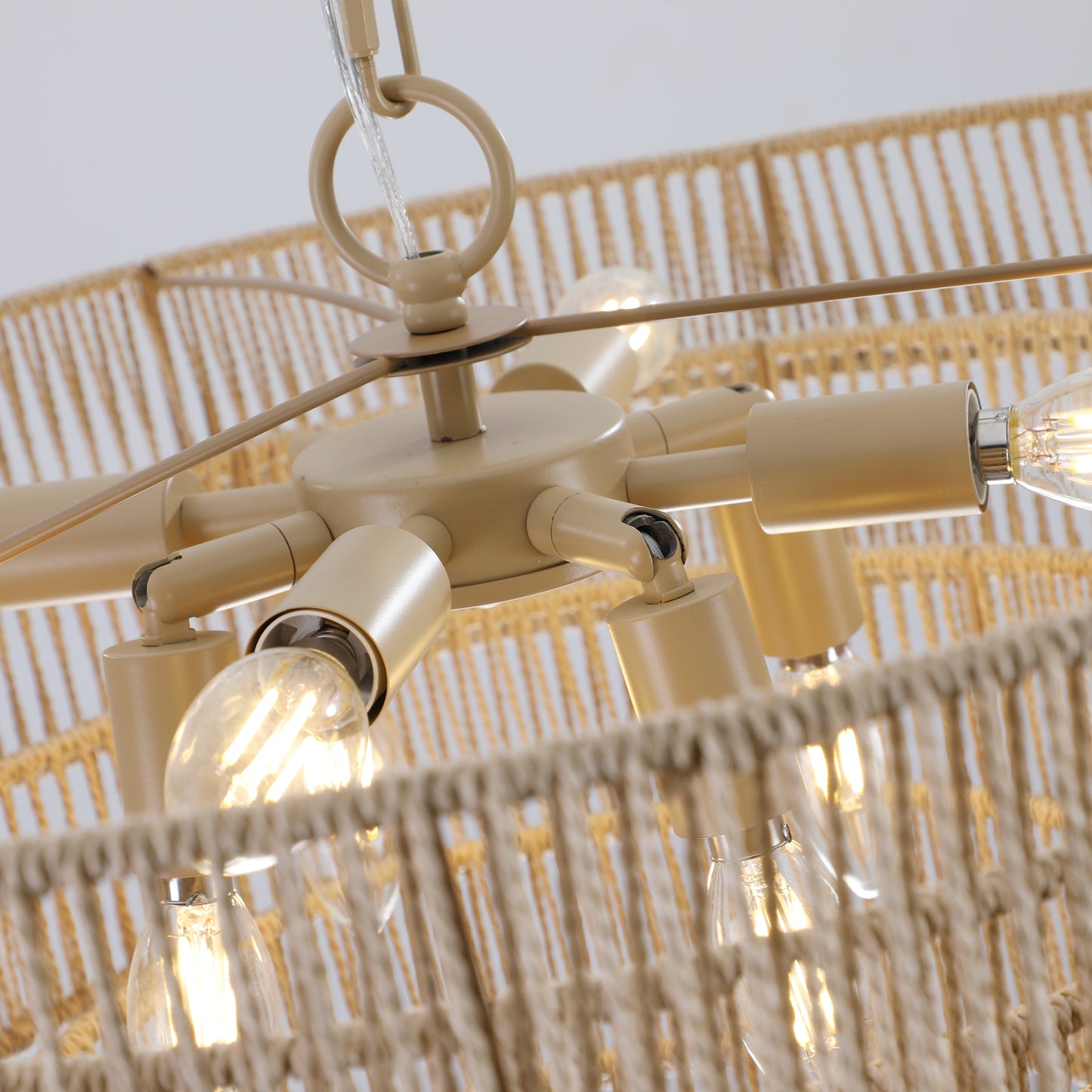 Closeup of a tan chandelier with a woven rope shade and exposed Edison bulbs