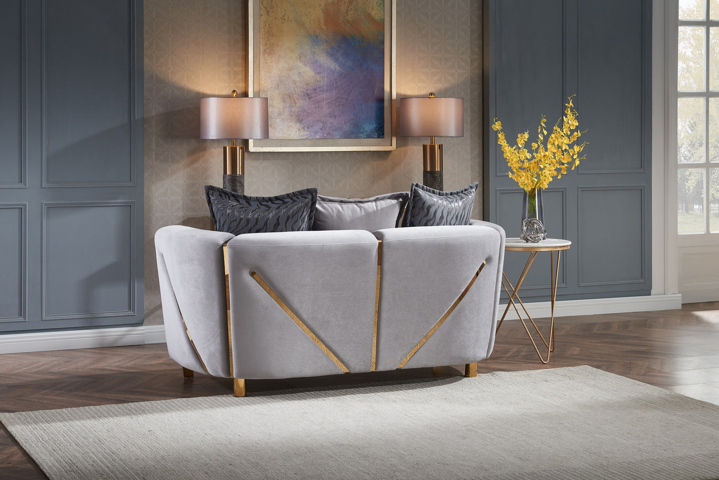 Light grey velvet sofa with gold geometric accents and decorative throw pillows