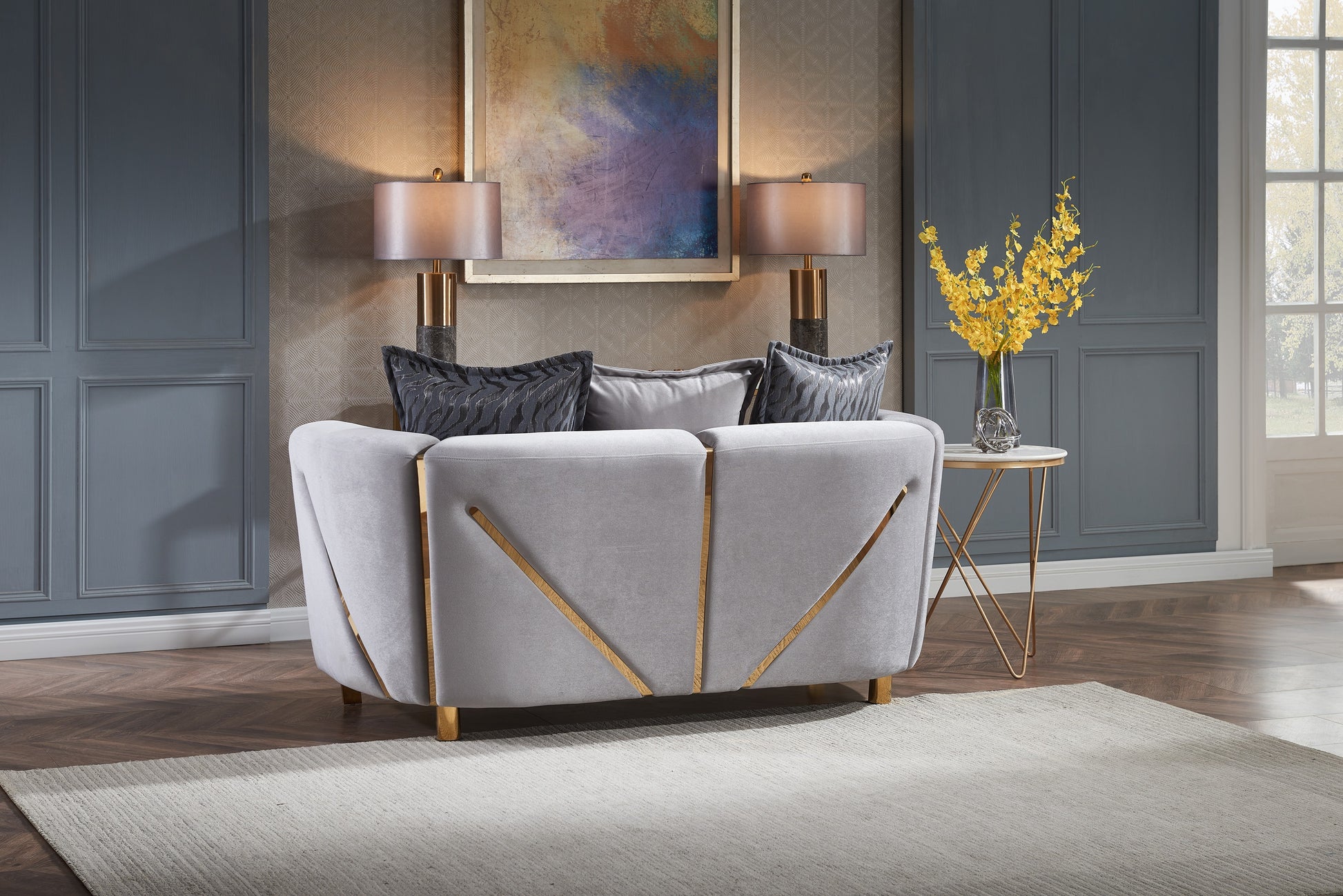 Light grey velvet sofa with gold geometric accents and decorative throw pillows