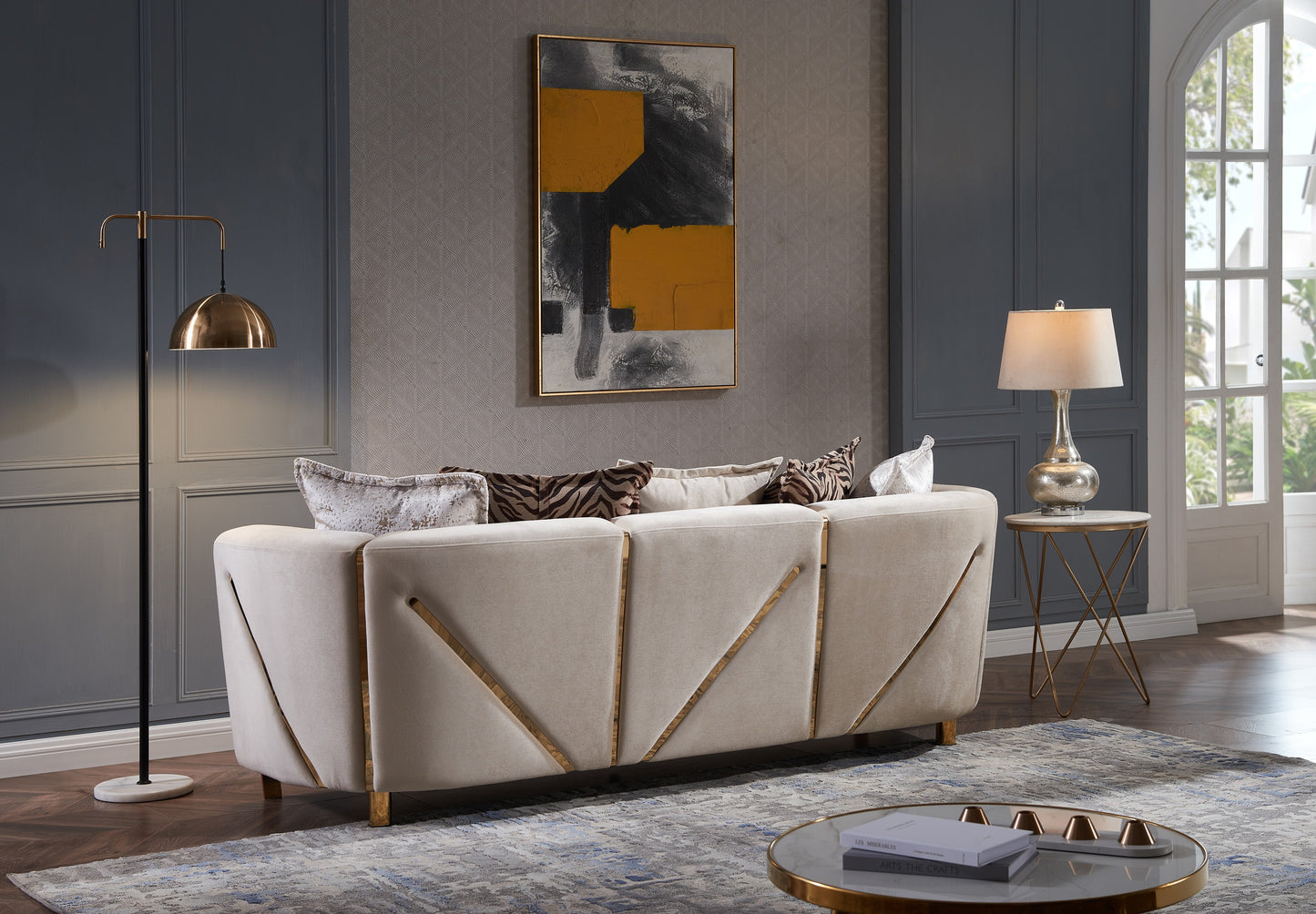 Elegant beige velvet sofa with gold geometric accents and abstract throw pillows for a modern living room