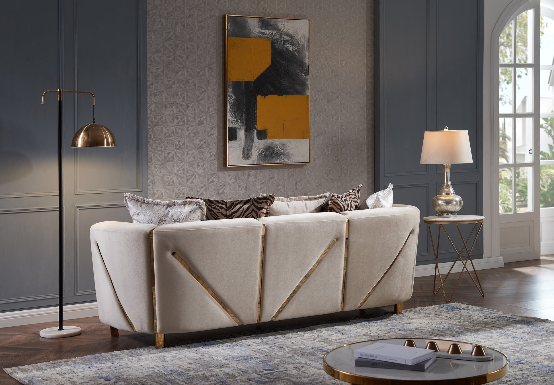 Elegant beige velvet sofa with gold geometric accents and abstract throw pillows for a modern living room